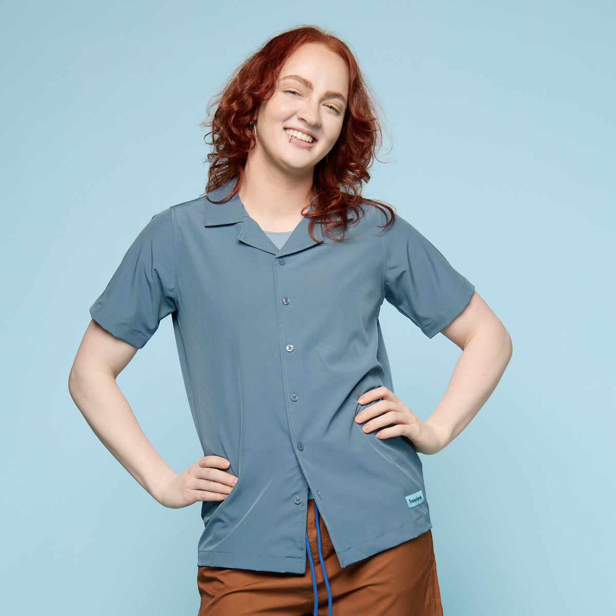 Steel blue gender-affirming swim shirt with button-up collar, front view, worn by trans masc model